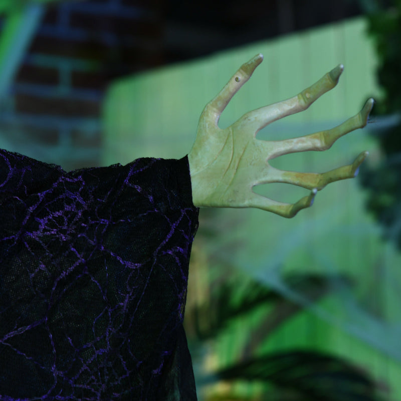 Close-up of the witch's pale clawed hand and black lace sleeve