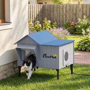 Cat house placed against a garden wall with a cat walking out