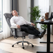 Man leaning back in the office chair with the footrest out beside a standing desk