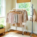 Lifestyle photo of the white double rod clothes rack with coats and hangers by a window