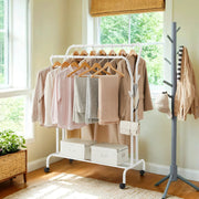 Lifestyle photo of the white double rod clothes rack with coats and hangers by a window