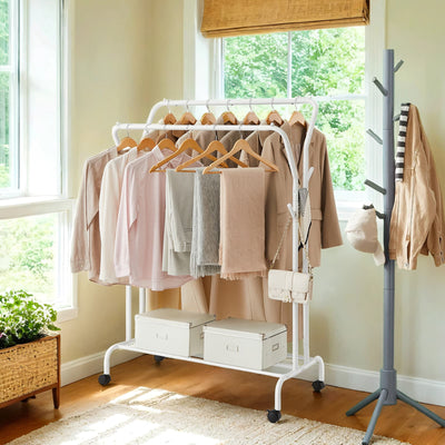 Lifestyle photo of the white double rod clothes rack with coats and hangers by a window