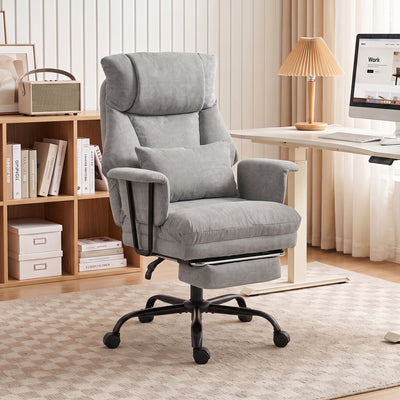 Grey office chair with footrest out in a home office setting beside a desk and bookshelf