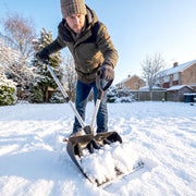 Man shovelling a driveway clear using both handles of the snow shovel