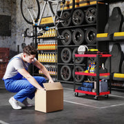 Mechanic crouching by a cardboard box with the loaded tool trolley in the garage behind