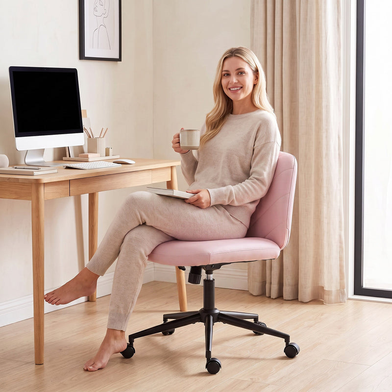 Woman sitting in the pink chair at a desk with a coffee cup and tablet