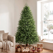 7ft artificial Christmas tree beside a sofa and window with a pile of wrapped gifts at its base