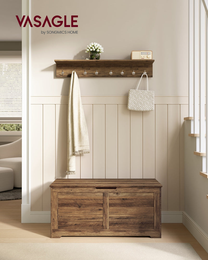 Honey brown shoe storage bench in a hallway beneath a matching wall shelf with hooks