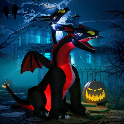 Inflatable two-headed dragon lit up at night in front of a haunted house with jack-o'-lanterns