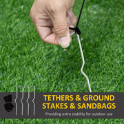 Hand pushing one of the 4 ground stakes into a lawn