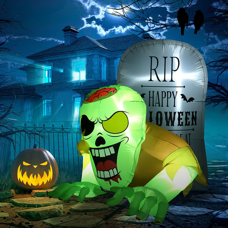 Inflatable zombie and tombstone lit up in a night garden beside a carved pumpkin