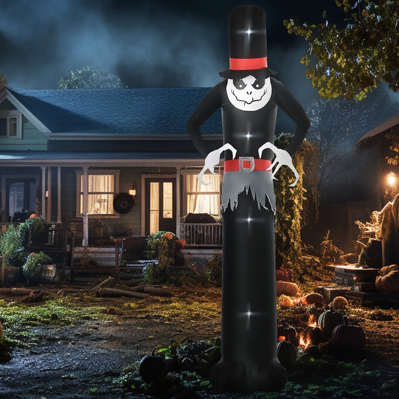 Tall ghost lit up on a lawn at night beside a house and pumpkins