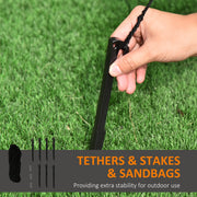 Hand pushing a black ground stake into grass beside the inflatable