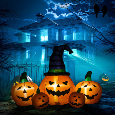 Inflatable pumpkin set glowing at night in front of a dark haunted house