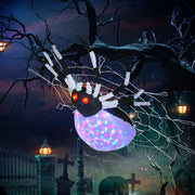 Inflatable spider hanging from a tree branch in a spooky graveyard Halloween scene