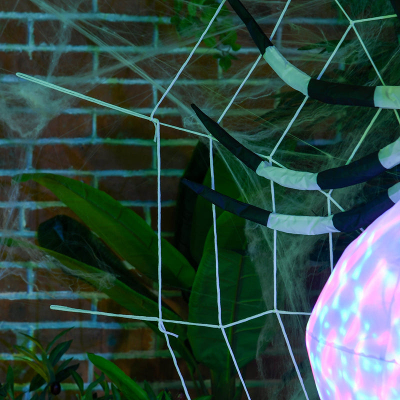 Close-up of the spider's striped legs against a brick wall decorated with fake cobwebs
