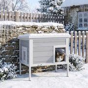Cat looking out from the entrance curtain of the PawHut insulated cat house in a snowy garden
