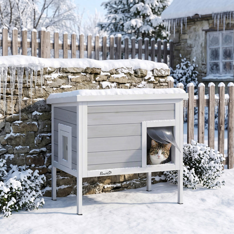 Cat looking out from the entrance curtain of the PawHut insulated cat house in a snowy garden