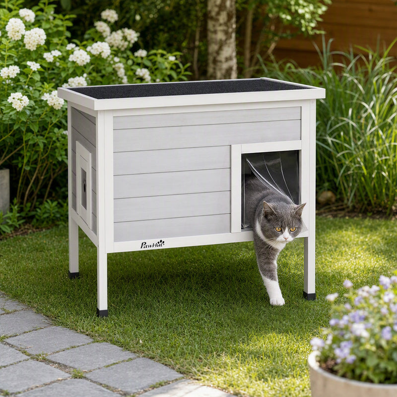 Cat walking out through the front entrance curtain of the PawHut cat house on grass