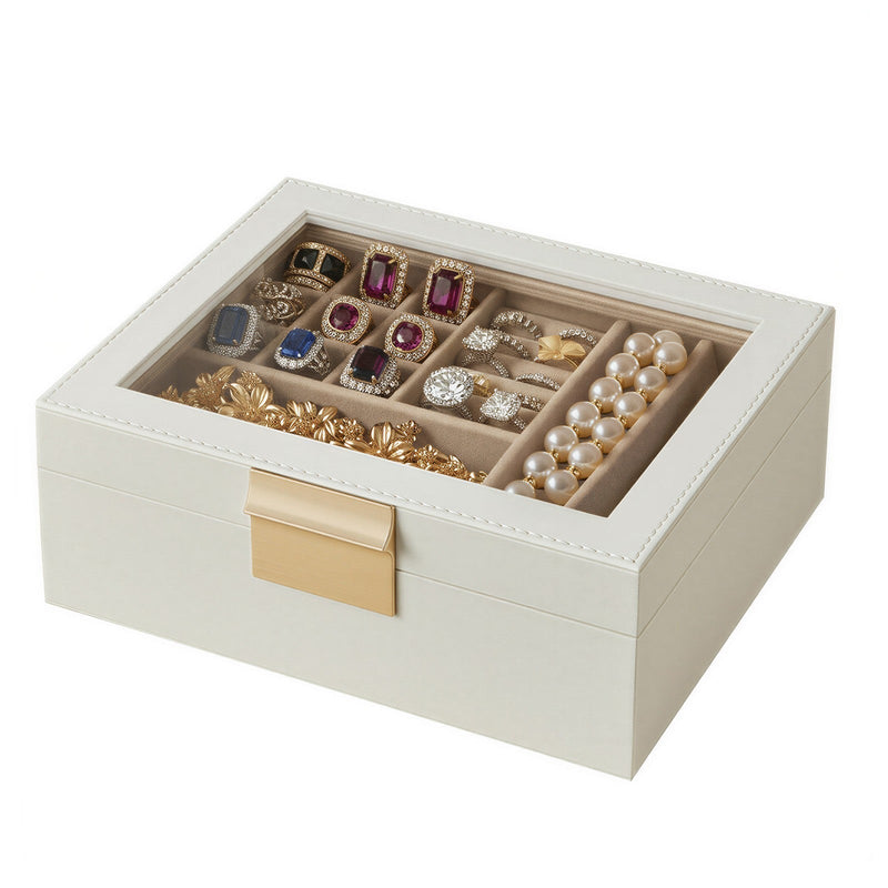 Glass lid jewellery box with rings, earrings and pearls visible in the top tray