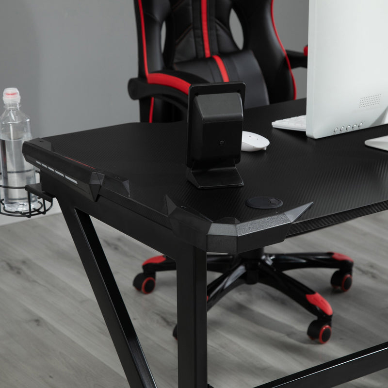 Close-up of the black desk corner with a gaming chair and monitor behind it
