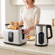 Woman placing croissants in the toaster beside the kettle in a bright kitchen