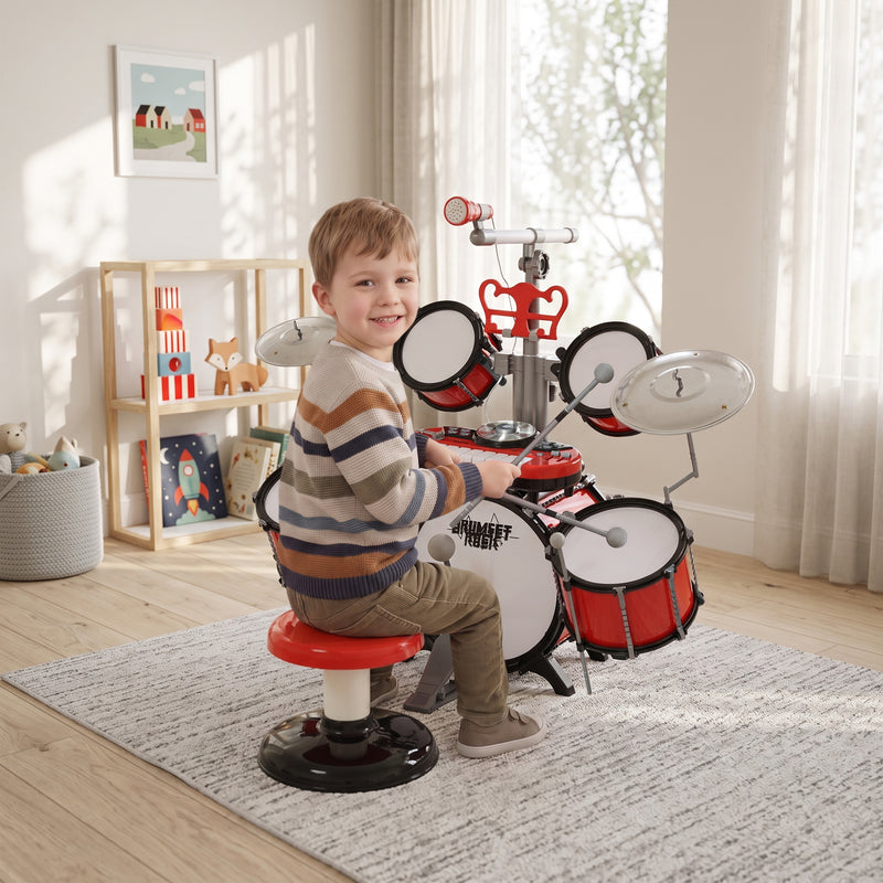 Child playing the red drum kit and keyboard at home