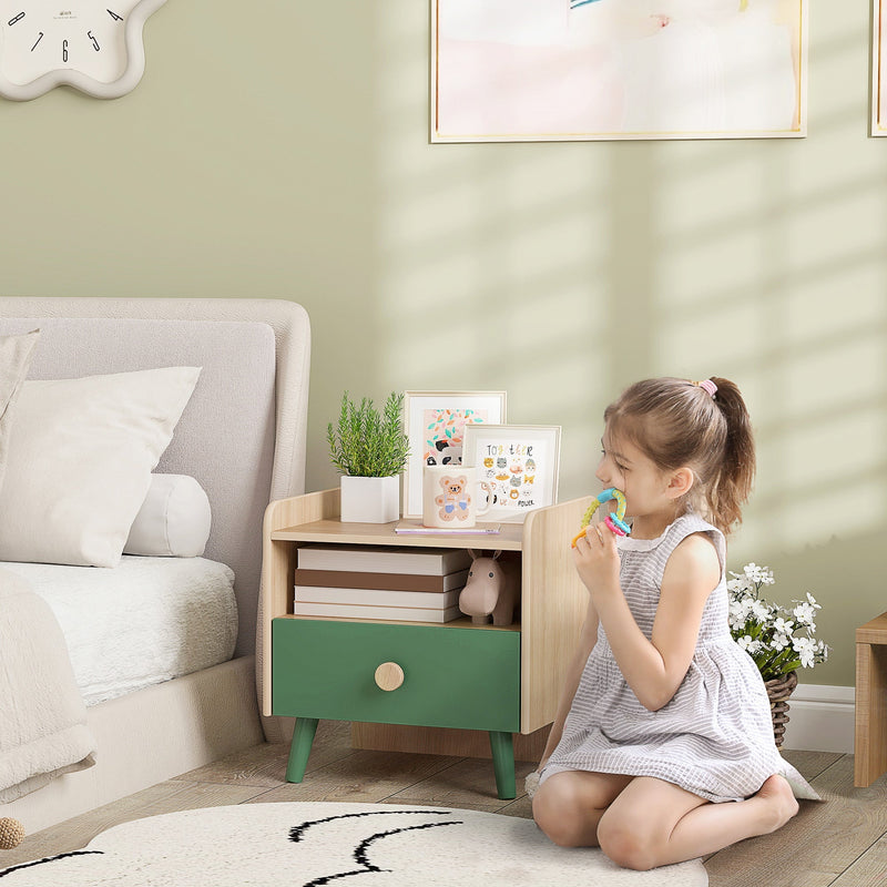 Child kneeling beside the green bedside table displaying books and framed pictures on top