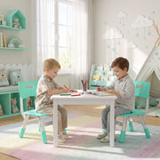 Two boys colouring at a table on kids chairs in a playroom with a play tent