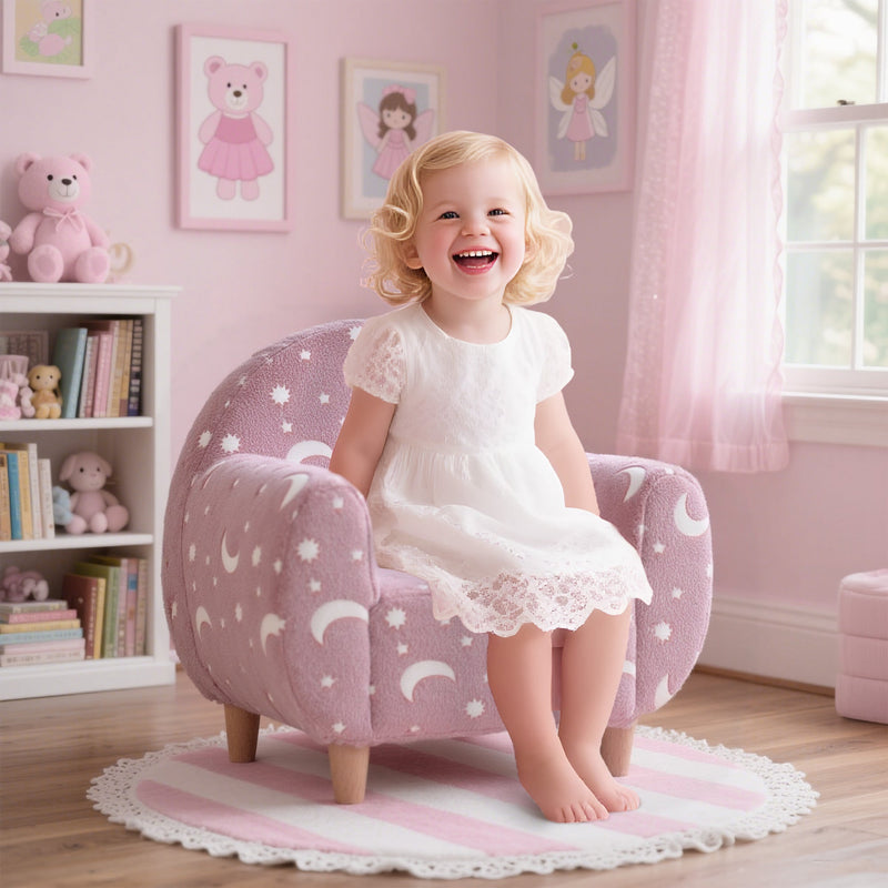 Toddler girl sitting in the pink kids armchair in a pink bedroom