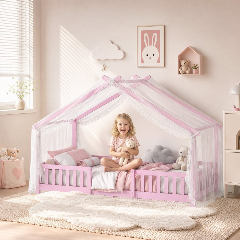 Child sitting inside the pink house bed frame under a sheer canopy with plush toys