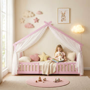Child reading inside the pink house bed frame with sheer canopy drapes