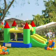 Green, yellow and blue bouncy castle on a lawn with children playing and balloons nearby