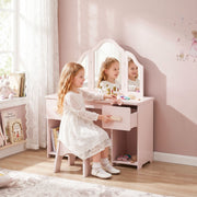 Girl sitting at the pink dressing table with a drawer open in a pink bedroom