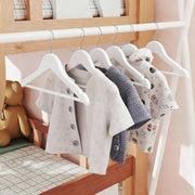 Kids wooden hanger holding a folded top over the trouser bar