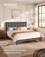 Slate grey upholstered king size bed in a sunlit bedroom with a robot vacuum beside the frame