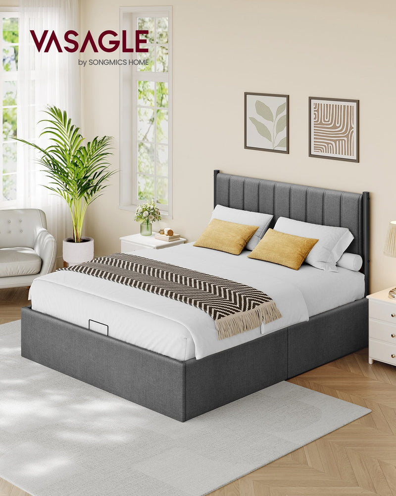 The made-up king bed in a bright bedroom with a white nightstand and yellow cushions