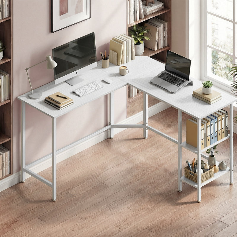 Corner desk in a pink home office holding a monitor, laptop and desk lamp