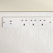 Close-up of a phone and earbuds charging from the desk's USB ports