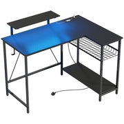 Black L shaped gaming desk with monitor stand, mesh shelf and bottom shelf on a white background