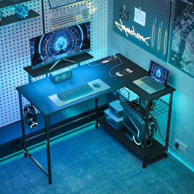 L shaped gaming desk with blue LED lighting in a bedroom corner with monitor, keyboard and laptop