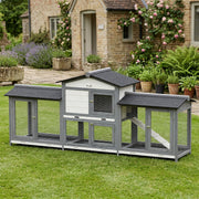 Rabbit hutch standing on a lawn in front of a stone cottage with roses and lavender behind