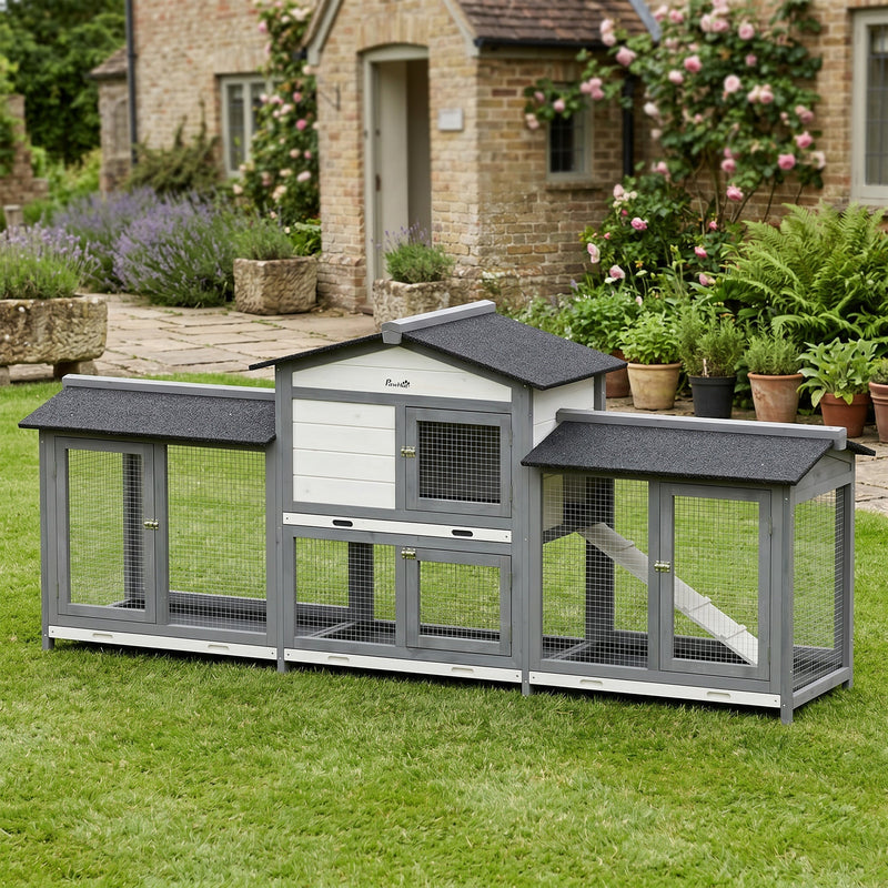 Rabbit hutch standing on a lawn in front of a stone cottage with roses and lavender behind