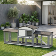 Rabbit hutch on a lawn beside a modern patio with potted olive and palm plants