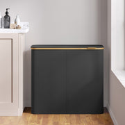 Closed black laundry hamper placed against a wall beside a bathroom vanity unit