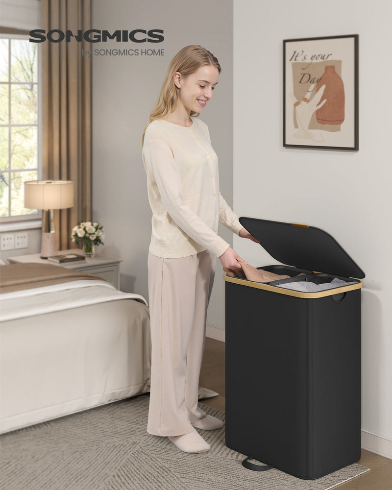 Woman placing laundry into an ink black hamper beside a bed