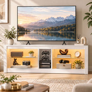 White TV stand in a living room with warm LED lighting, a wall TV above and ornaments on the shelves