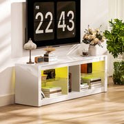 White TV stand with yellow LED lighting under a wall-mounted TV beside a plant