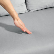 Close-up of a hand pressing into the tufted velvet cushion