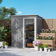 The light grey shed against a garden fence with its sliding door open, showing pipework and tools stored inside